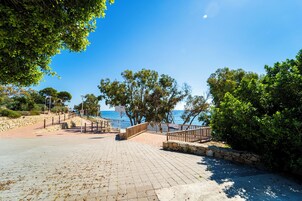 Un sendero pavimentado con barandillas de piedra y vista al mar.