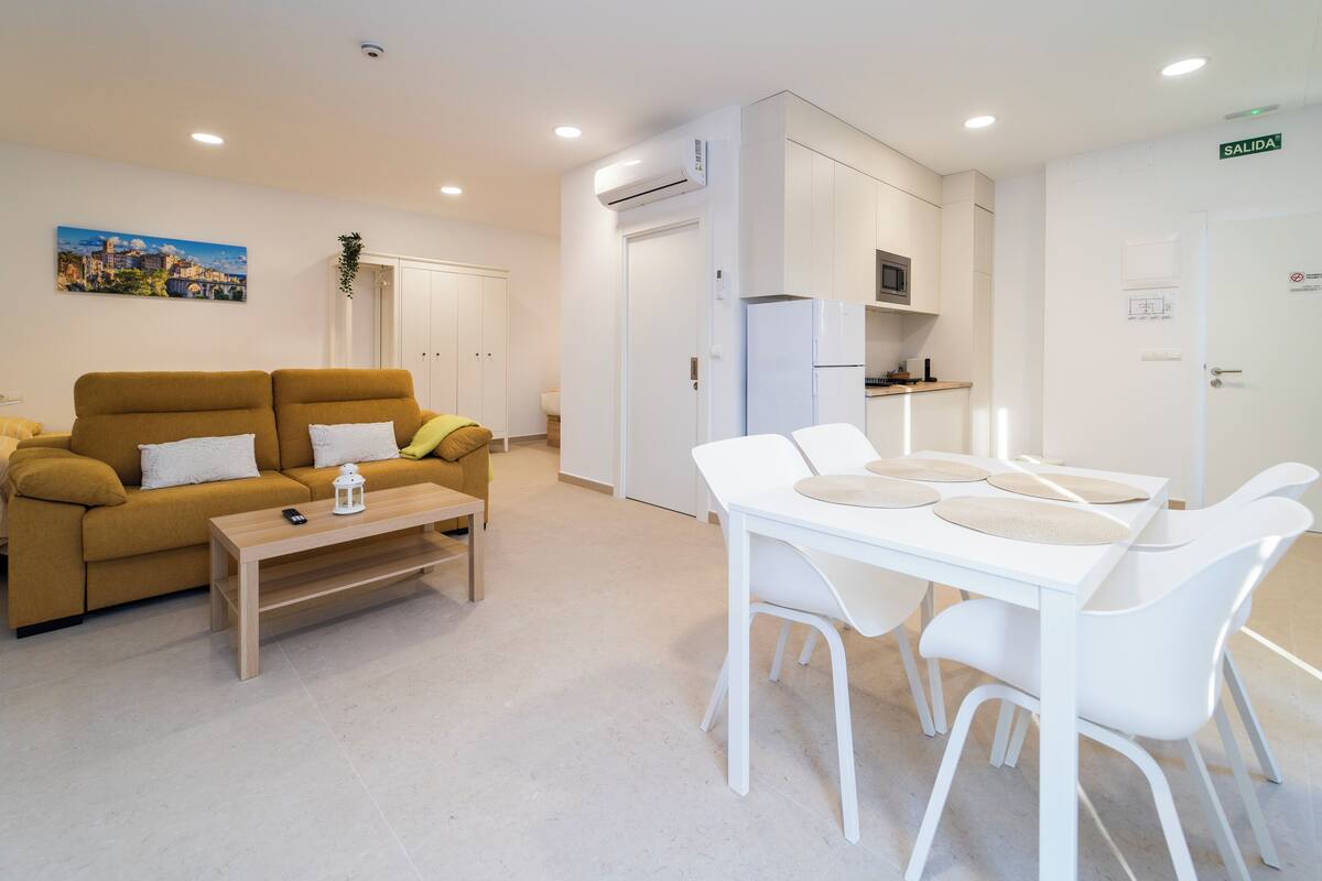 Un salon moderne comprenant un canapé, une table basse et un coin repas avec une table et des chaises.