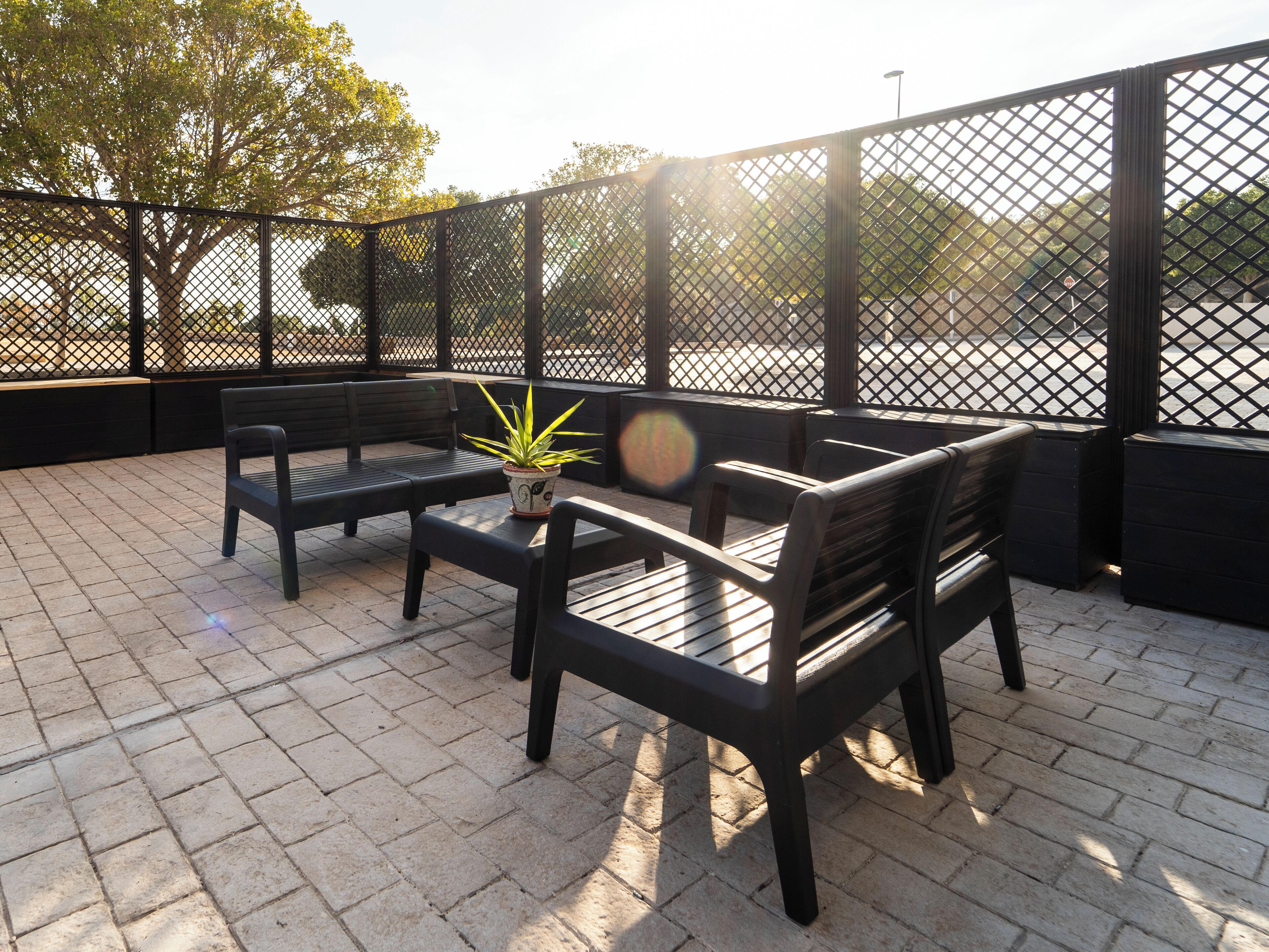 Un espace extérieur aménagé avec une table et deux chaises, un pot de fleurs et une clôture.
