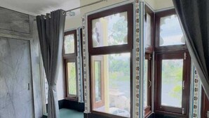 A room with a large window, a wooden ceiling, and a green cushioned bench. - Hotel Moxa Inn (Udaipur)