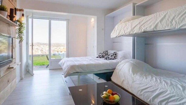 A modern bedroom with bunk beds, a glass table with fruit, and a city view. - Charming studio for 4 in Ciboure with terrace (Ciboure)