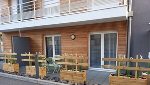 Ein modernes Gebäude mit Holzfassade, Sitzgelegenheiten im Freien und einem Balkon.