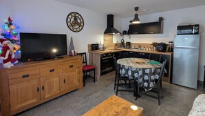 Eine kleine Küche mit Essbereich, einem Holzkasten, einem Kühlschrank und einem Weihnachtsbaum.