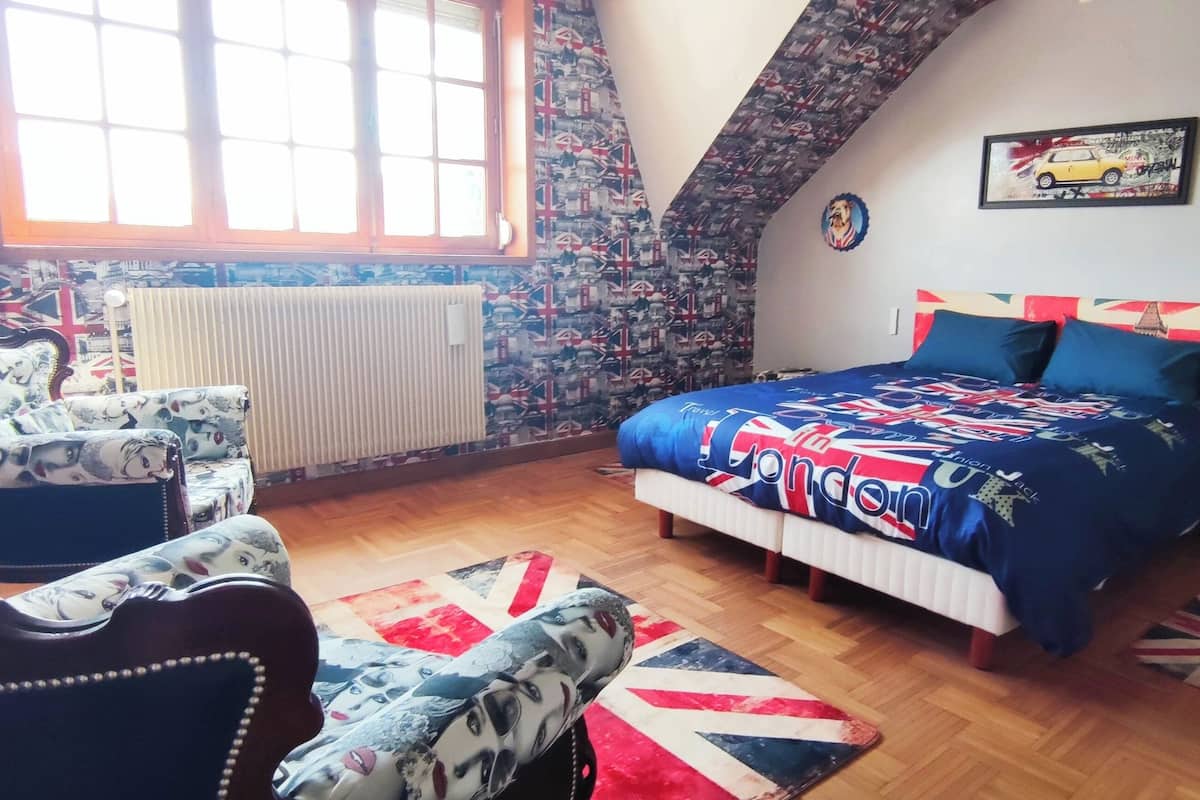A bedroom with a bed, a chair, a radiator, and a window.