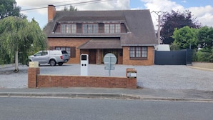 A two-story house with a brick facade, a driveway, and a parked pickup truck. - L'Emmanuella (Isbergues)