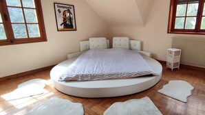 A bedroom with a round bed, two windows, a radiator, and a poster on the wall. - L'Emmanuella (Isbergues)