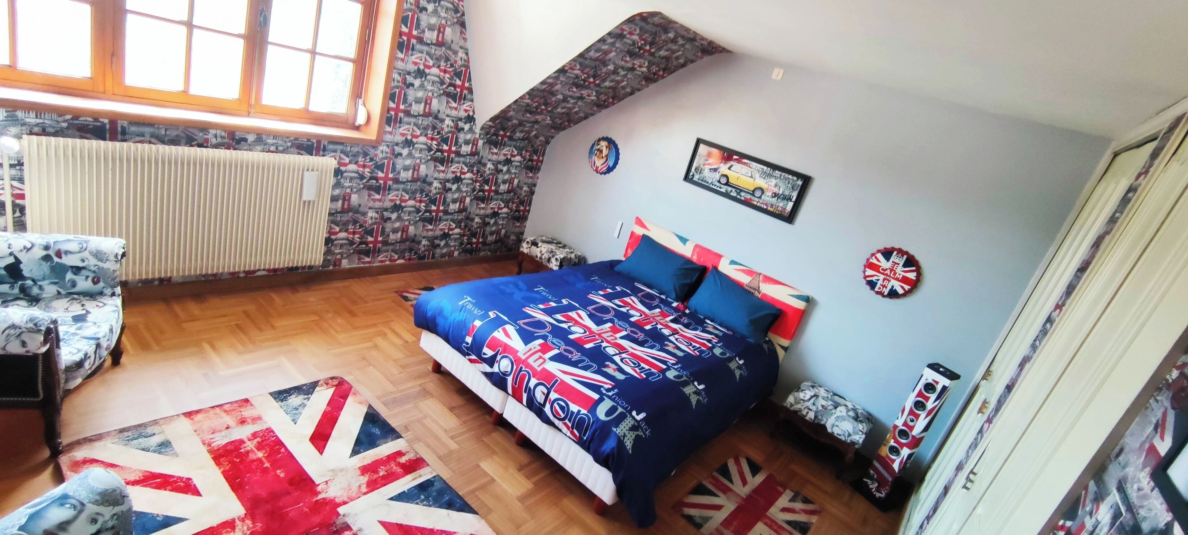Un dormitorio con cama, ventana, radiador y pared con diseño.
