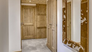 A hallway with wooden doors and a large mirror with a rustic frame. - Comfortable apartment in Villard-sur-Doron for 6 people with parking (Villard-sur-Doron)