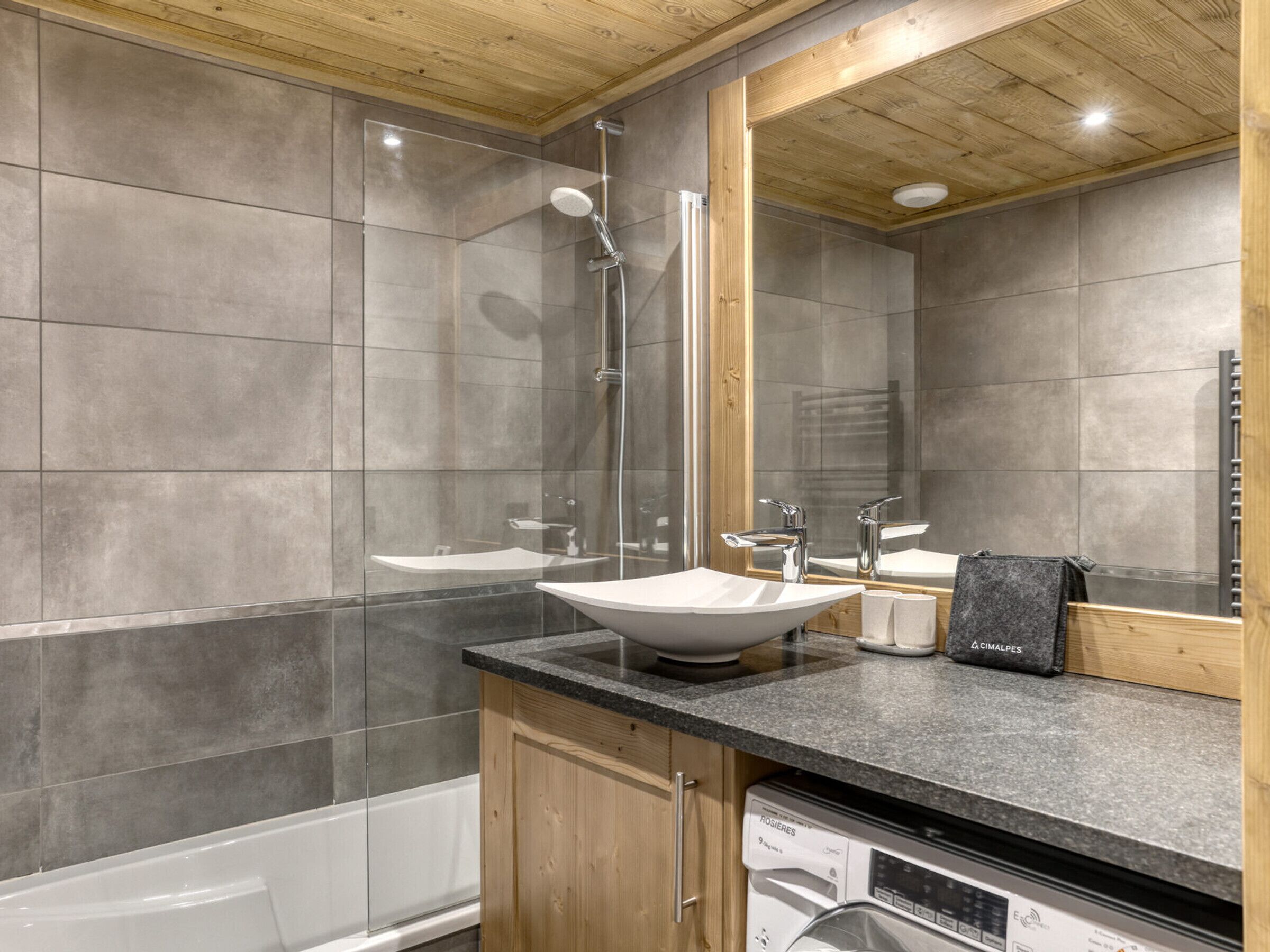 Un baño moderno con una bañera independiente, una ducha con mampara de vidrio y un espejo grande.
