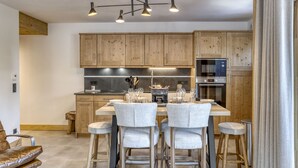 A modern kitchen with wooden cabinets, a central island with bar stools, and stainless steel appliances. - Comfortable apartment in Villard-sur-Doron for 6 people with parking (Villard-sur-Doron)