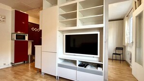Ein modernes Wohnzimmer mit integriertem Fernseher, weißen Schränken und einer roten Akzentwand.