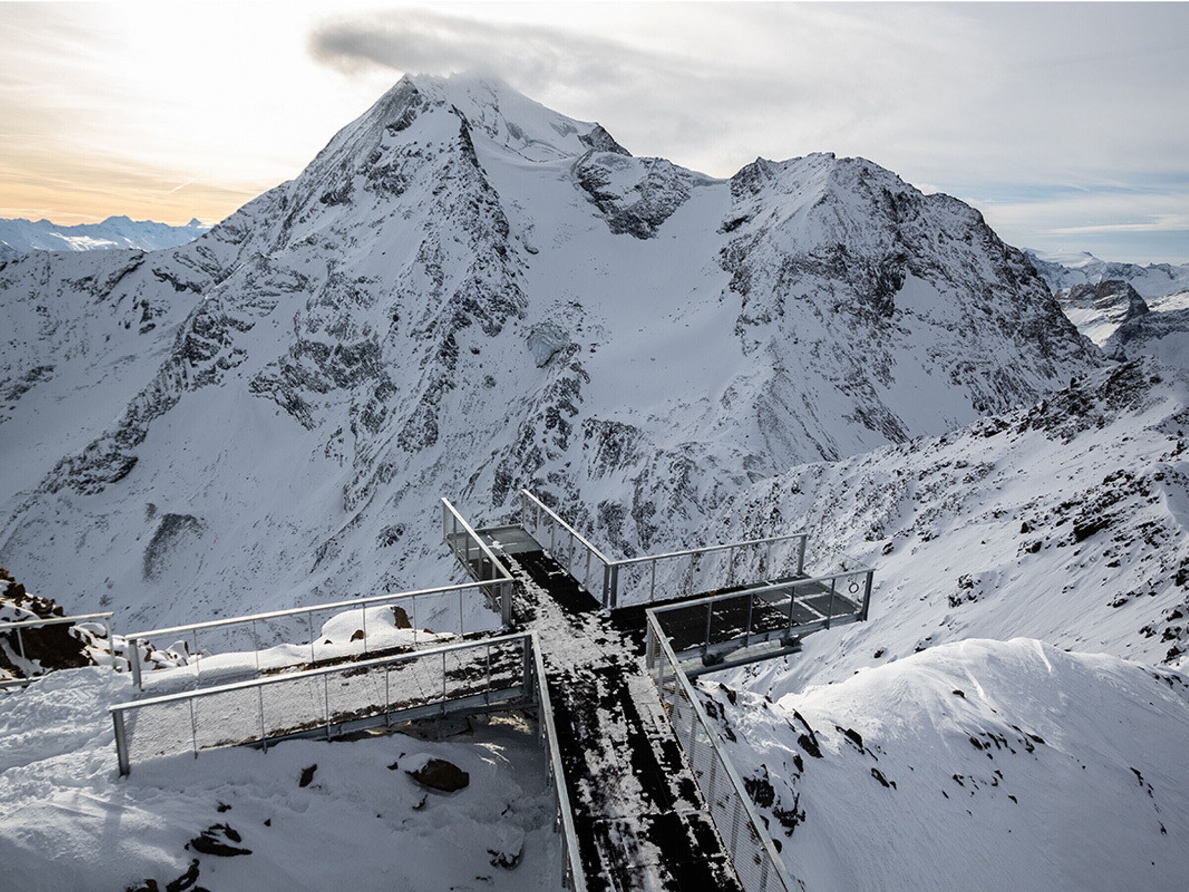 Une montagne enneigée, avec un escalier métallique qui monte jusqu'au sommet.