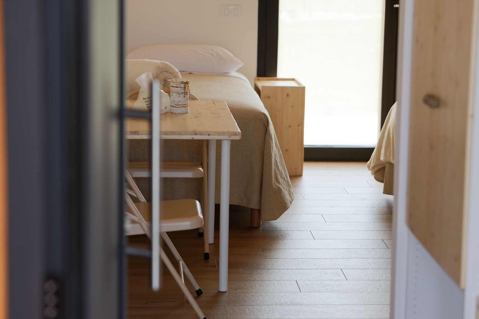 Ein kleines, gemütliches Zimmer mit einem Bett, einem Holztisch und einem Stuhl.