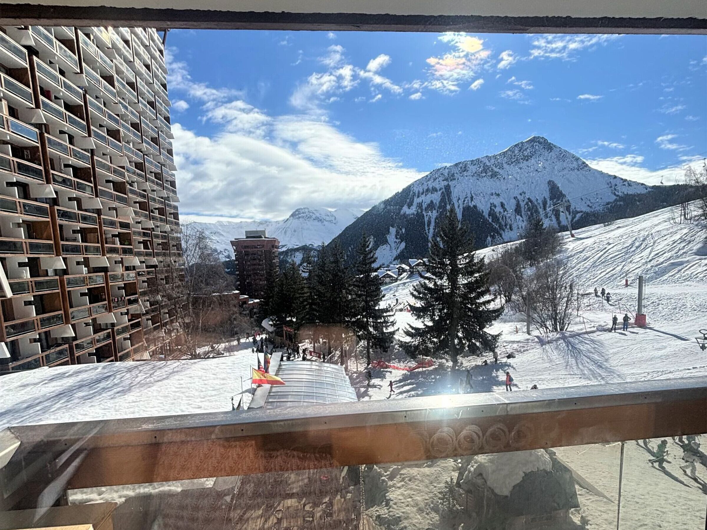 Ett snötäckt berg med en skidbacke och en modern byggnad med en unik fasad.