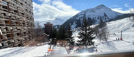 A snow-covered mountain with a ski slope and a modern building with a unique facade.