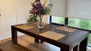 Une table à manger ornée d’un vase de fleurs, de deux sets de table et d’un banc.