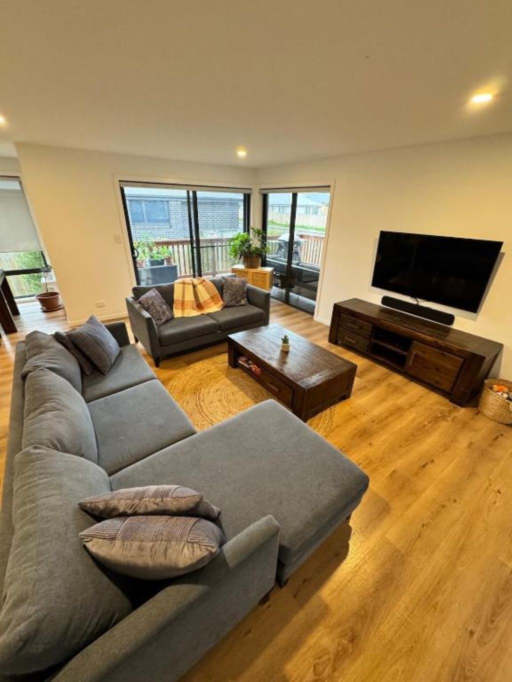 A modern living room with a grey sectional sofa, a coffee table, and a TV on a wooden stand.