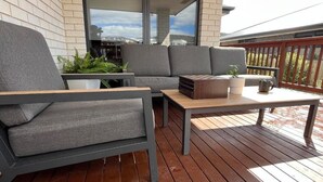 Un espace extérieur moderne aménagé avec un canapé et des fauteuils, une table en bois et une plante en pot.