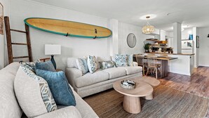 Un salon moderne avec un canapé, une table basse et une planche de surf accrochée au mur.