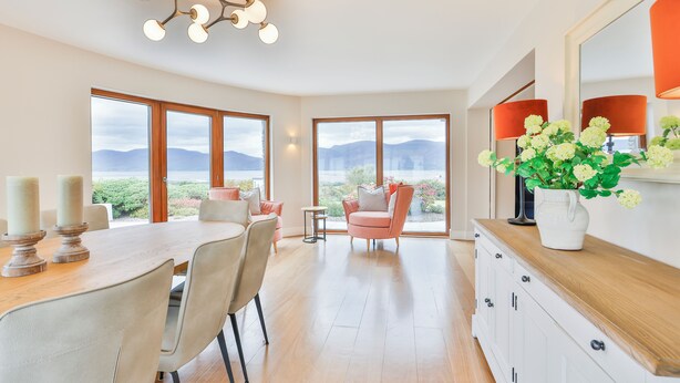 Un comedor amplio con una mesa y sillas de madera, ventanas grandes con vistas a la montaña y una lámpara moderna.