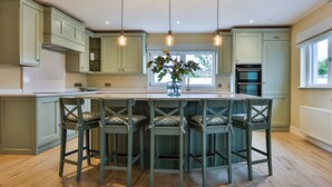 Una cocina con isla central, taburetes de bar e iluminación colgante.
