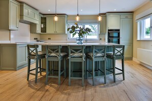 Een keuken met een centraal eiland, barstoelen en hanglampen.
