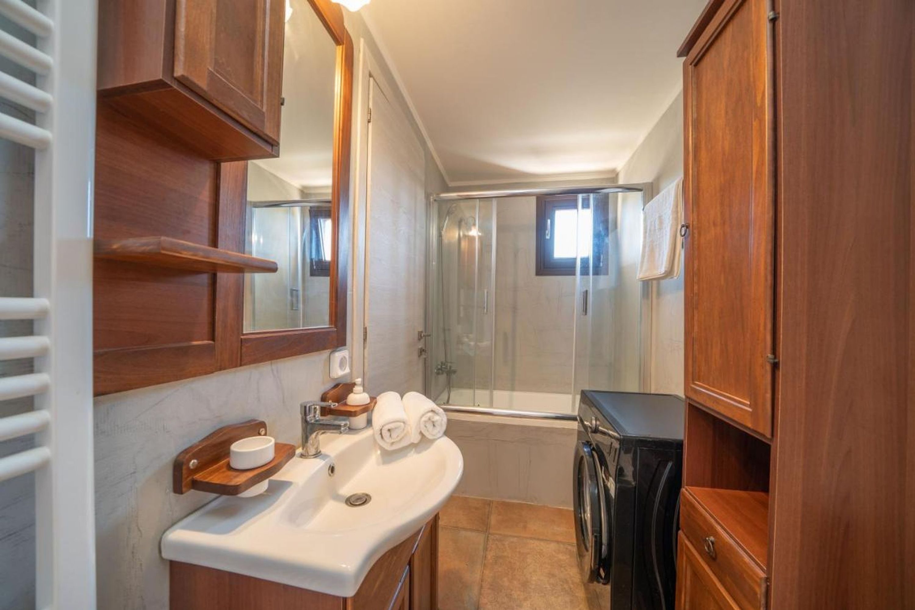 A bathroom with a sink, mirror, wooden cabinets, a shower, and a toilet.