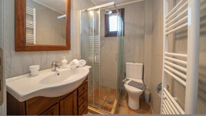 Ein Badezimmer mit einer Duschkabine, einem weißen Waschbecken und einer Toilette.