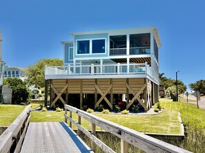 A two-story house with a wooden deck and a covered area. - Docks and Dunes: A spacious 5-bedroom beach house in Oak Island, perfect for 14 guests! (Oak Island)