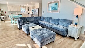 A modern living room with a sectional sofa, a coffee table, and a side table with a lamp. - Oceanview retreat in Oak Island, sleeps 12, perfect for families and a dog! (Oak Island)