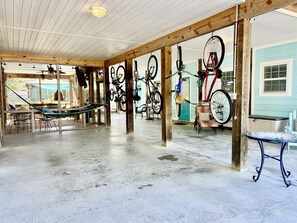 A covered outdoor area with bicycles, a hammock, and a table.