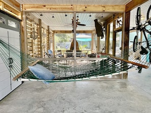 A hammock in a room with a concrete floor, wooden walls, and a view of the outdoors.