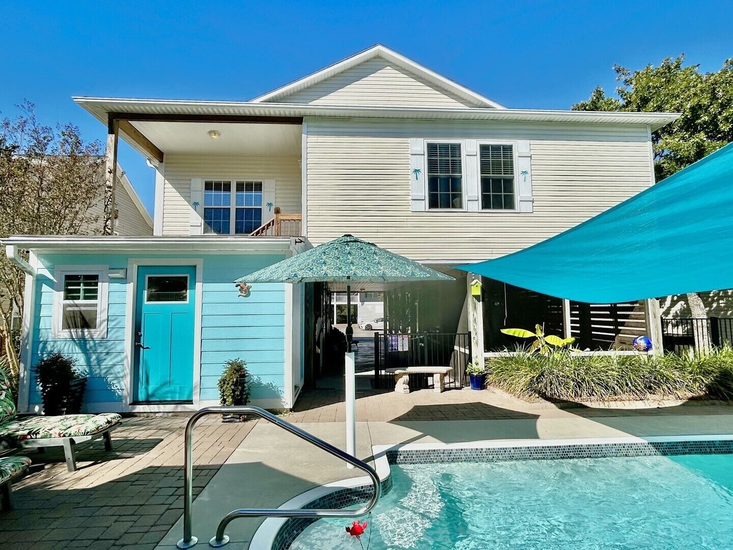 Une maison à deux étages avec une piscine, un patio couvert et un petit jardin.