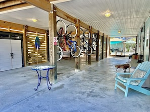 A covered outdoor area with bicycles, a table, and chairs.