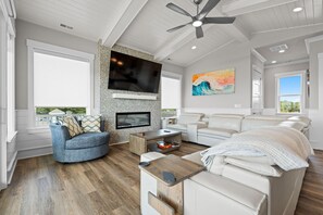 Un salon moderne avec un téléviseur, un canapé, une table basse et un ventilateur de plafond.