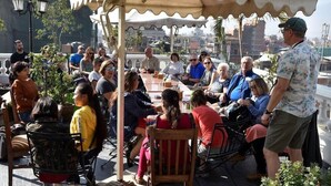 A group of people seated at an outdoor table under a canopy, with a cityscape in the background. - Hotel Excelsior Ltd (Kathmandu)