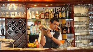 A bar area with shelves of liquor bottles and glasses. - Hotel Excelsior Ltd (Kathmandu)