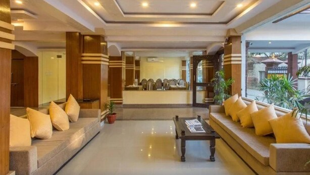 Un vestíbulo de hotel con mostrador de recepción, zonas de estar y una mesa de centro.