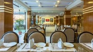 Comedor de hotel con mesas dispuestas para los huéspedes, destacando un mostrador central y una distribución de asientos.