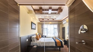 Habitación de hotel moderna con una cama grande, un separador de vidrio y vistas a la ciudad.
