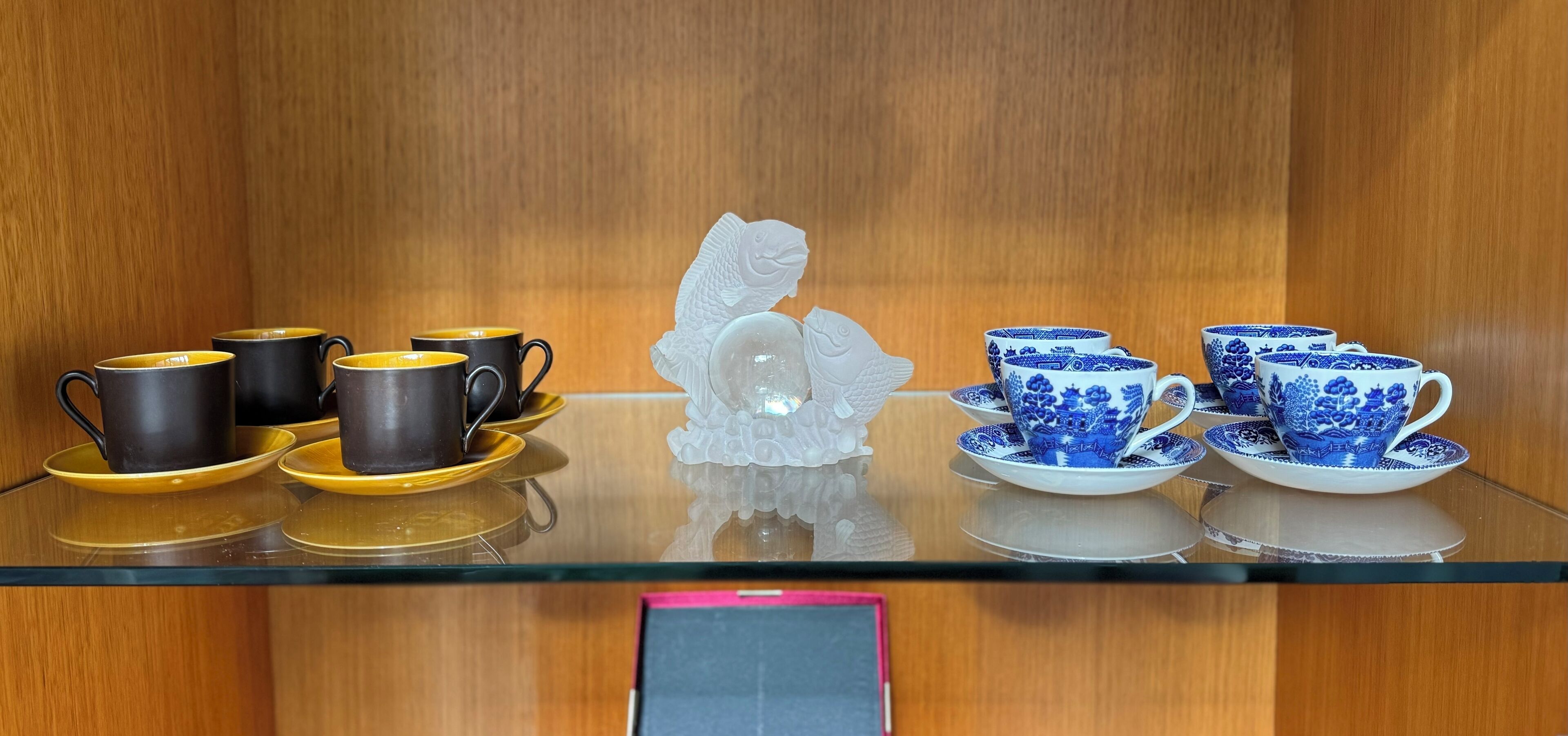 A display of black and blue ceramic cups and saucers on a glass table.