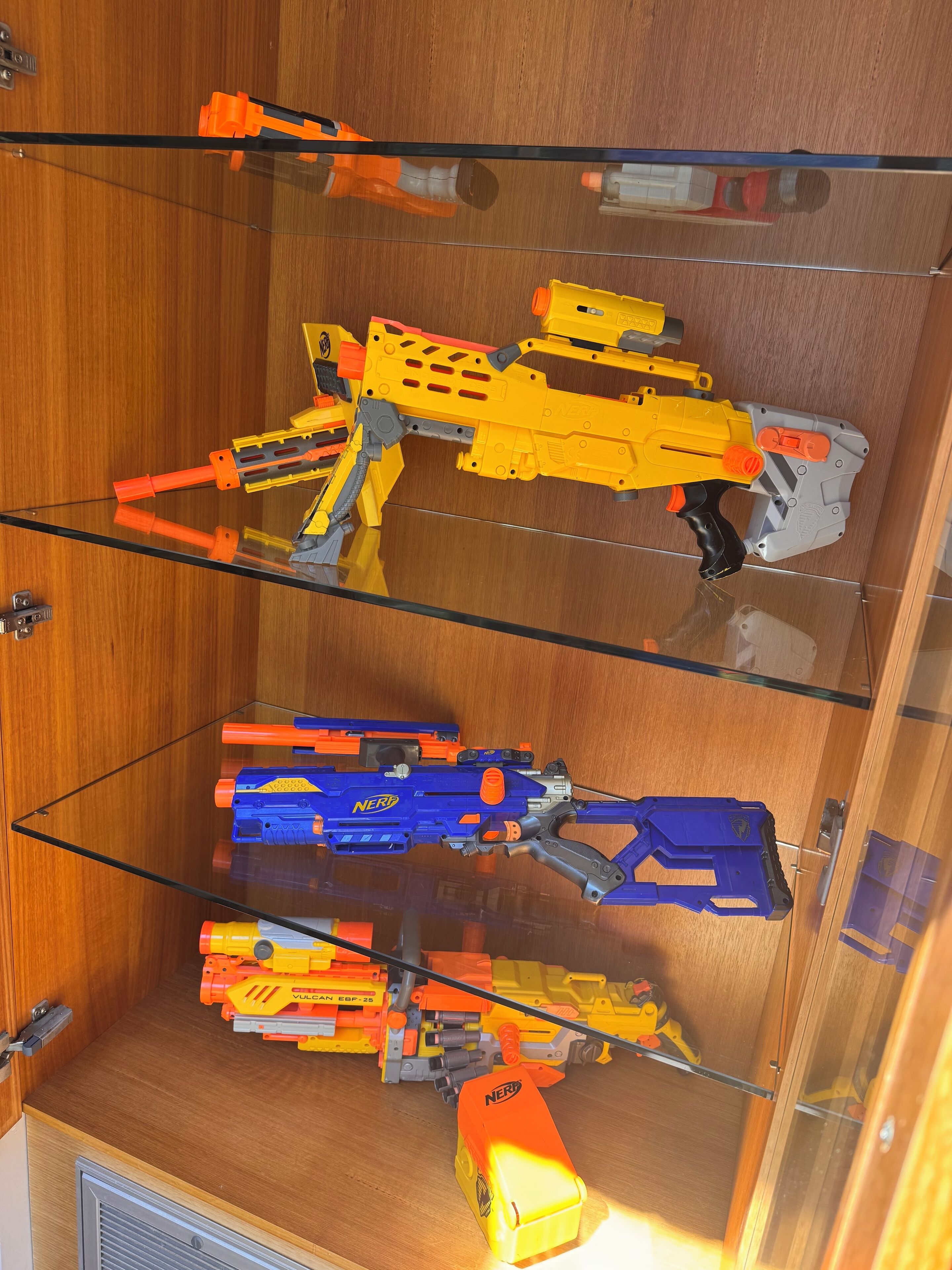 A storage unit with shelves holding various toy blasters.