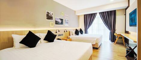 A hotel room with two beds, a desk, and a TV.