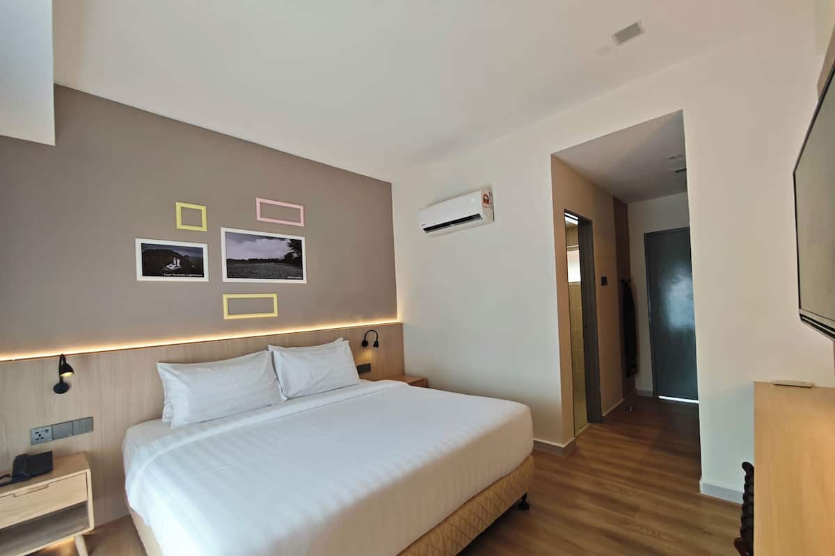 Habitación de hotel con una cama grande, mesitas de noche, aire acondicionado montado en la pared y cuadros enmarcados.