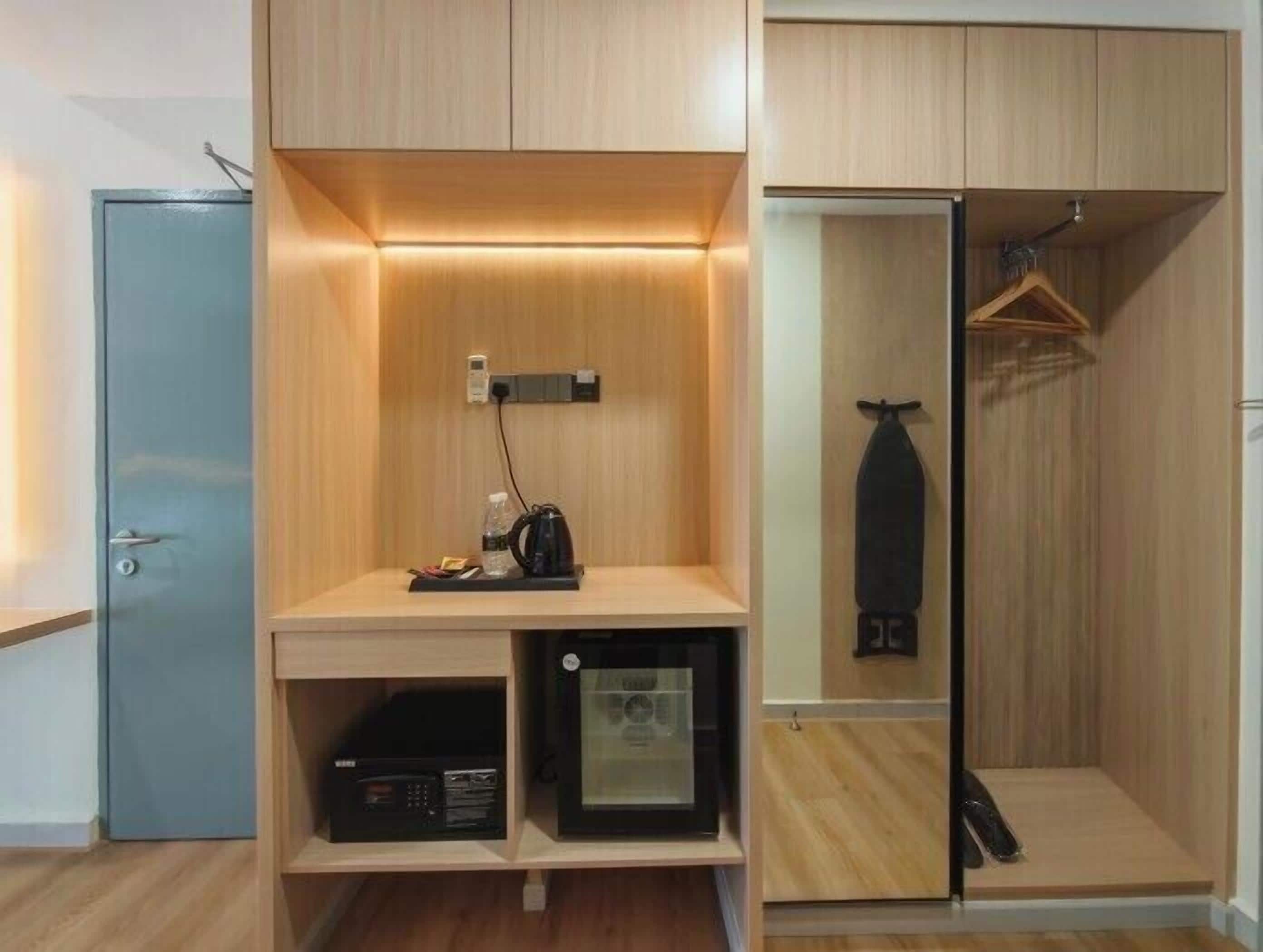 Habitación funcional con armario, una pequeña estantería que incluye una tetera, una radio y un perchero.