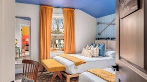 Hotellihuone, jossa on sänky, penkki, tuoli, ikkuna verhoineen ja näkymä ulos.