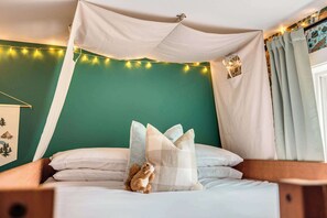 Een bed met hemelbed, kussens en een klein dier.
