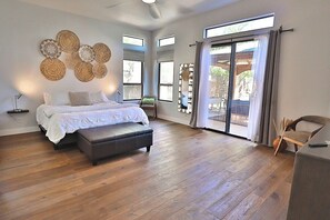 Ein Schlafzimmer mit einem großen Bett, einer Bank und Blick durch eine Schiebetür.