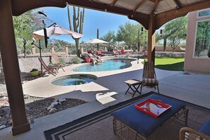 Ein überdachter Außenbereich mit Pool, Liegestühlen und Sonnenschirmen.