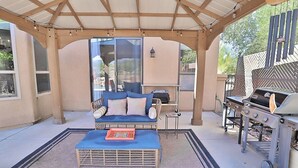 An outdoor patio with a covered seating area, a grill, and a view of the surrounding landscape. - Canyon Ridge Oasis (Tucson)